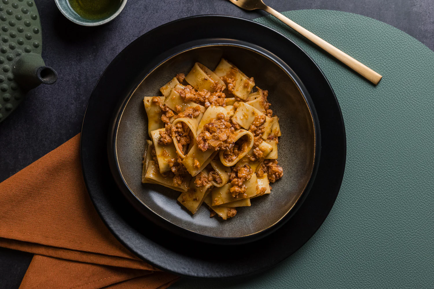 Zietta paccheri pasta with slow-cooked Neapolitan ragù served in a dark ceramic bowl